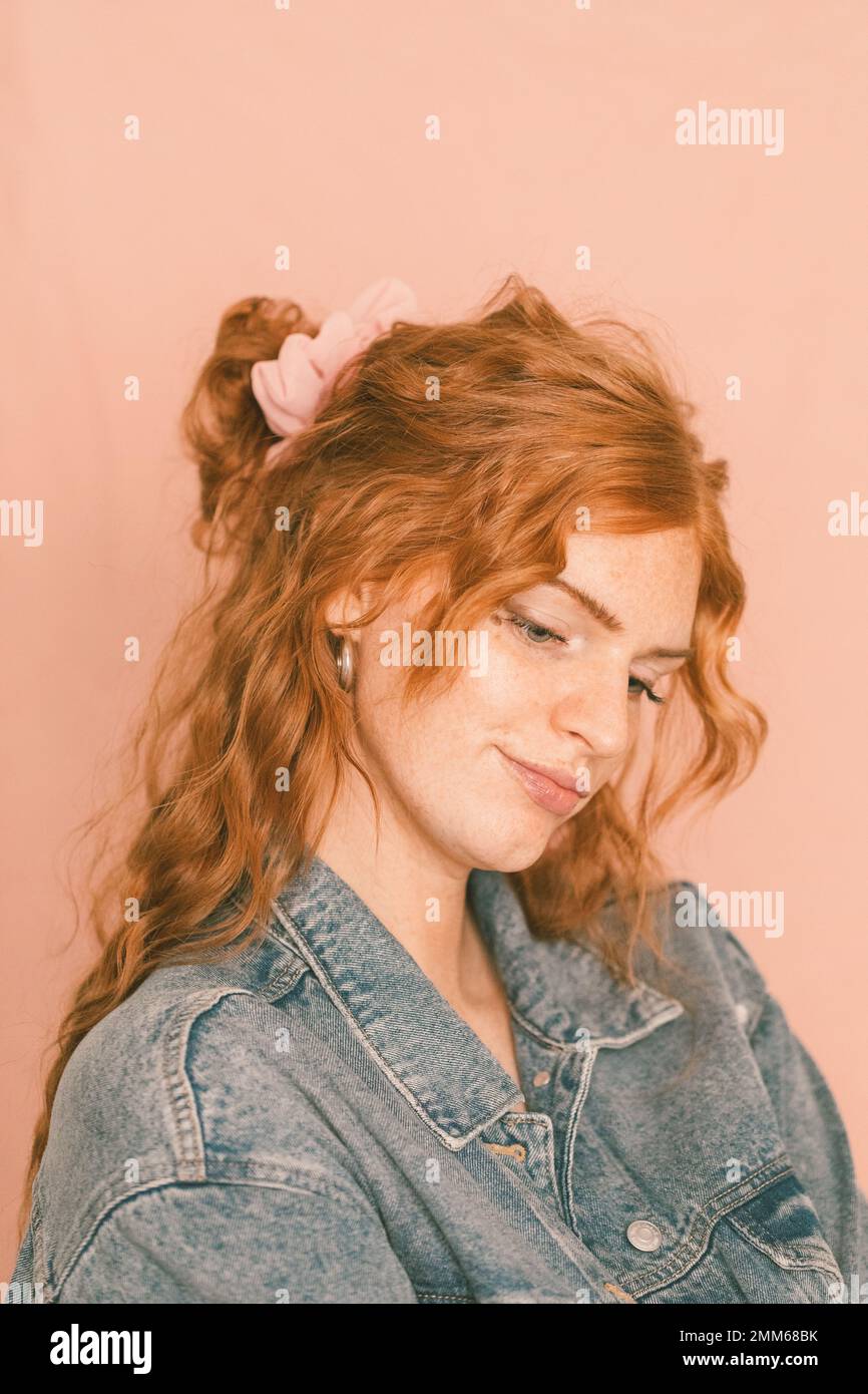 Portrait of woman smiling in denim jacket with pink scrunchie in Stock Photo