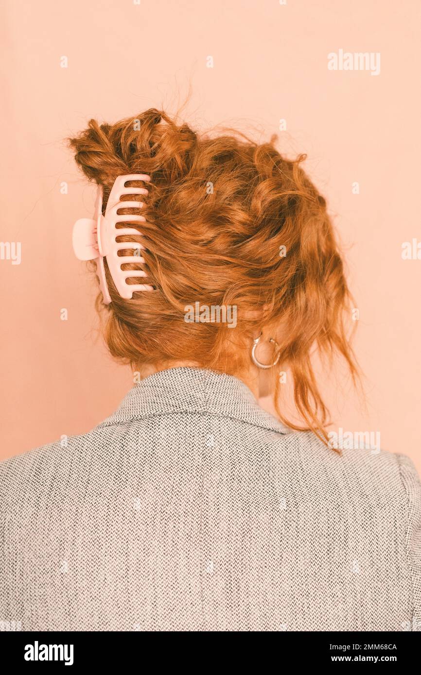 A business woman in a blazer with hair clip against a pink backg Stock Photo