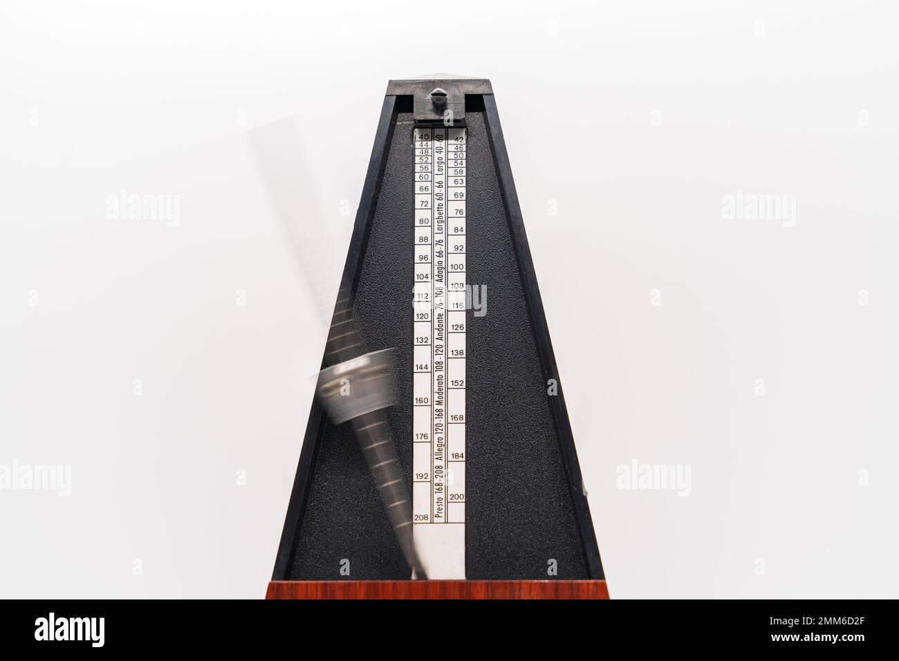 Old fashioned metronome with blurred arm indicating motion isolated on a white background Stock Photo