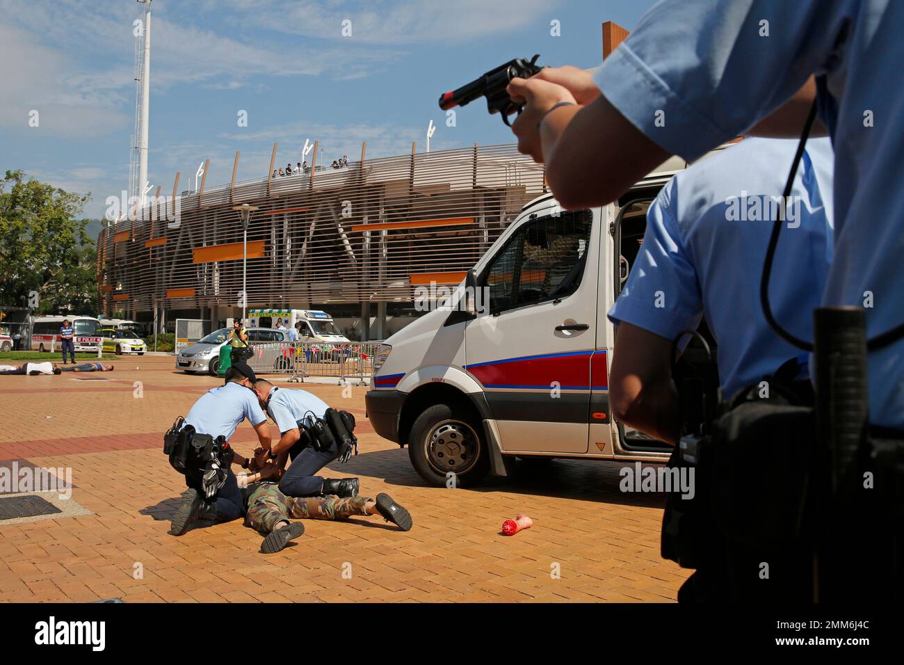 Police officers point their guns to a man who acts as a suspect in an antiterrorism drill at a