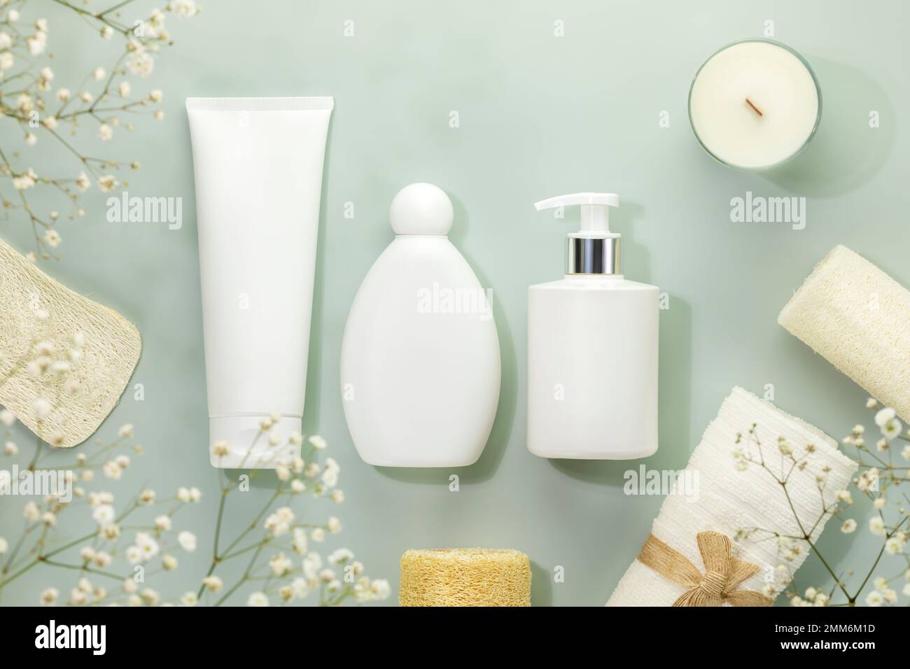 Eco friendly spa relax composition with mockup of beauty products, candle and spa accessories on blue background with white flowers. Wellness and skin Stock Photo