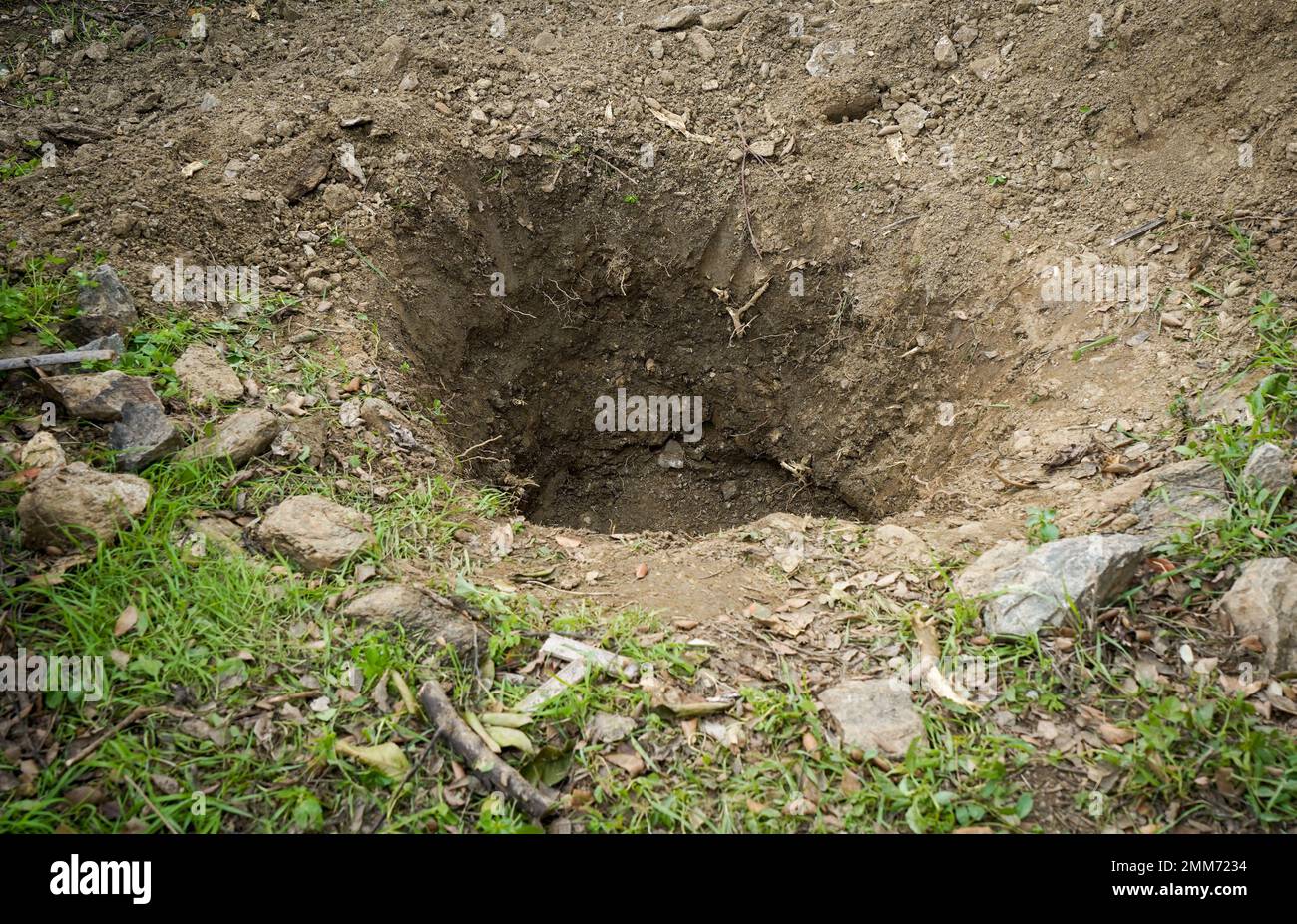 Deep hole in the ground in a garden. Stock Photo