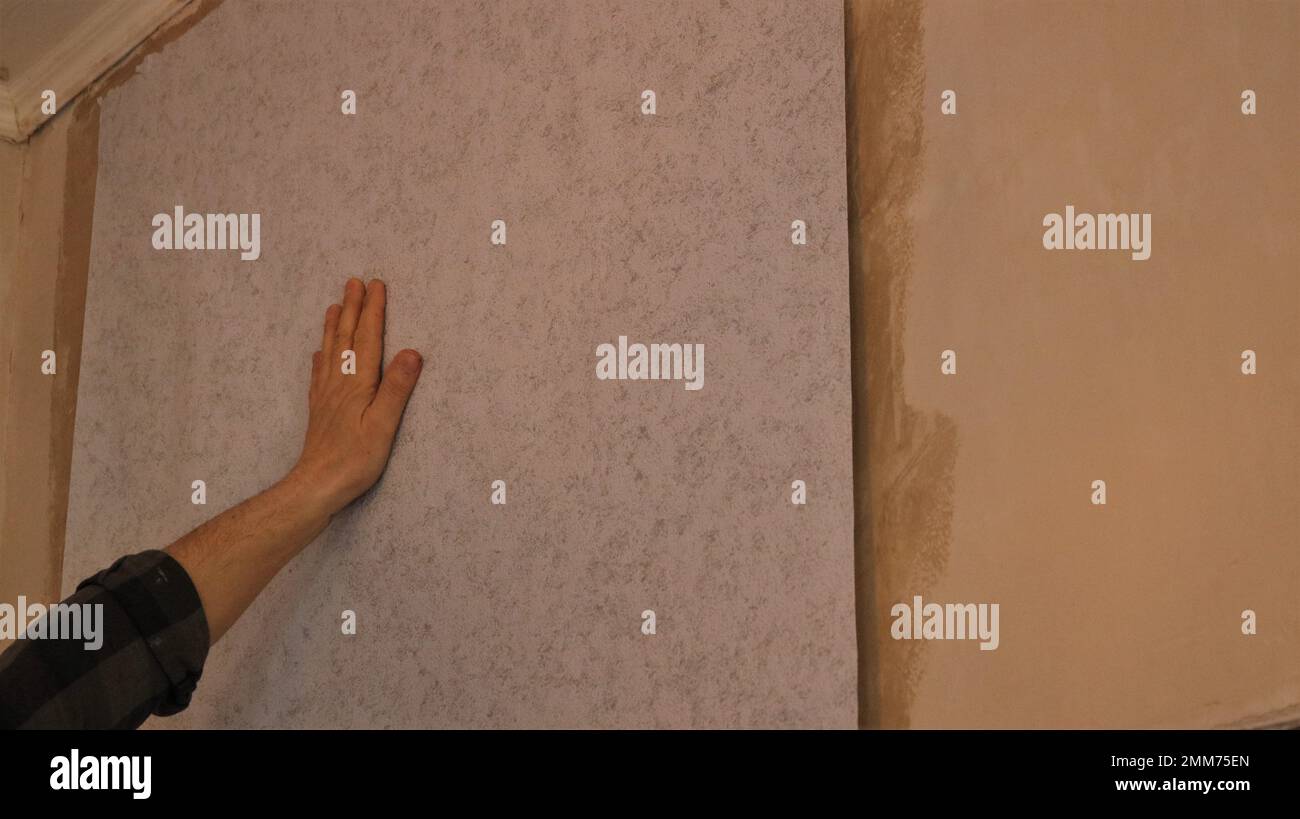 pasting wallpaper in a room on a prepared plastered wall, a male left