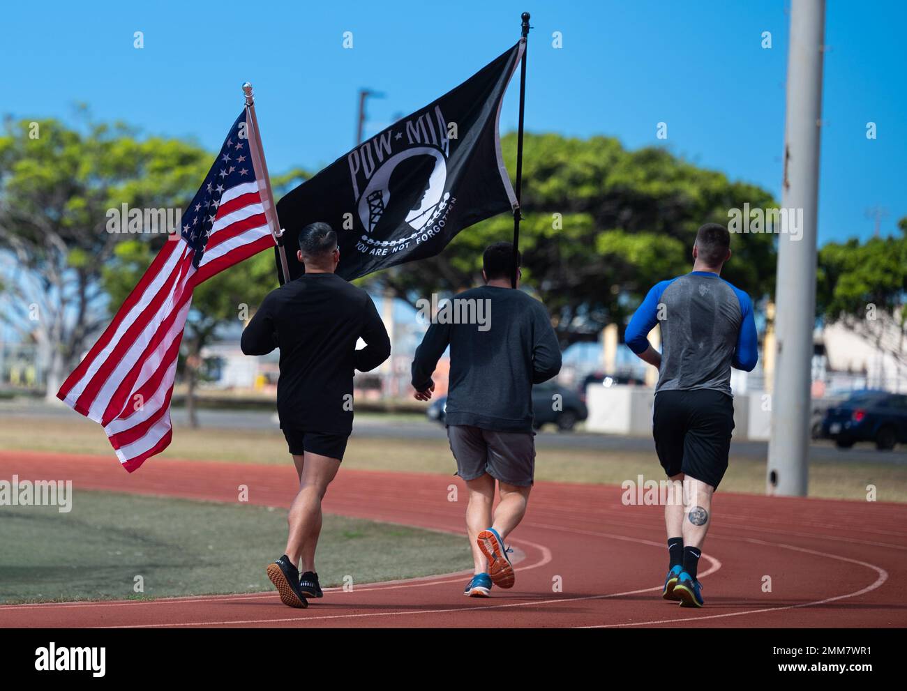 Airmen assigned to Joint Base Pearl Harbor-Hickam carry the American and POW/MIA flag in honor of POW/MIA week during a 24-hour run at Earhart Field on JBPHH, Hawaii, Sept. 15, 2022. The official U.S. POW/MIA flag was created through the efforts of POW/MIA family members to make the public aware of their loved ones who were being held prisoner or declared missing during the Vietnam War. Stock Photo