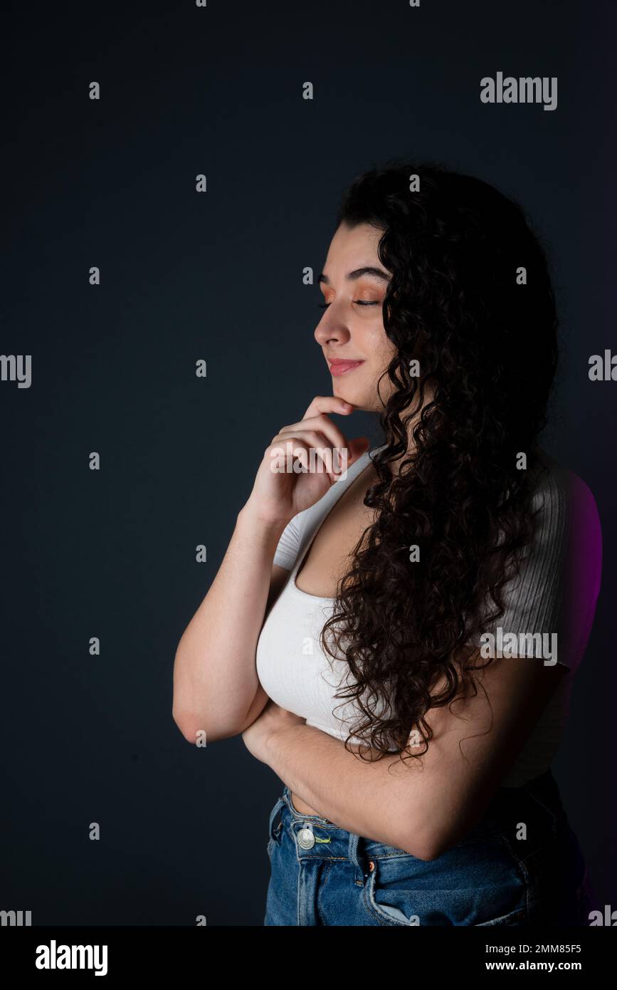 Portrait young woman in profile, beautiful and relaxed. Isolated against dark background. Stock Photo