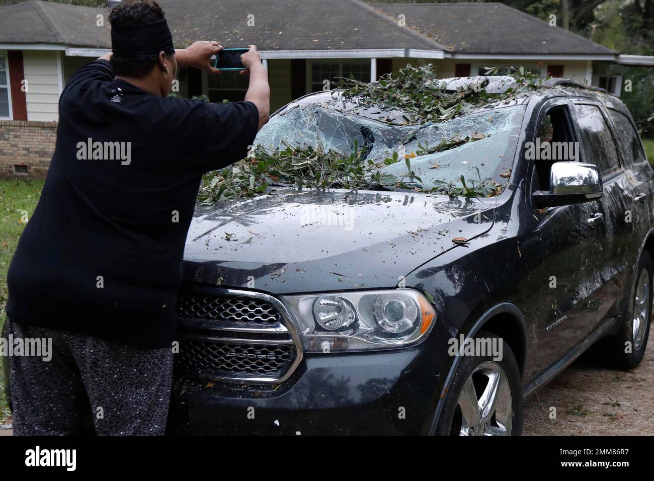 Jennifer Lyles takes a photograph of her SUV, one of three cars heavily
