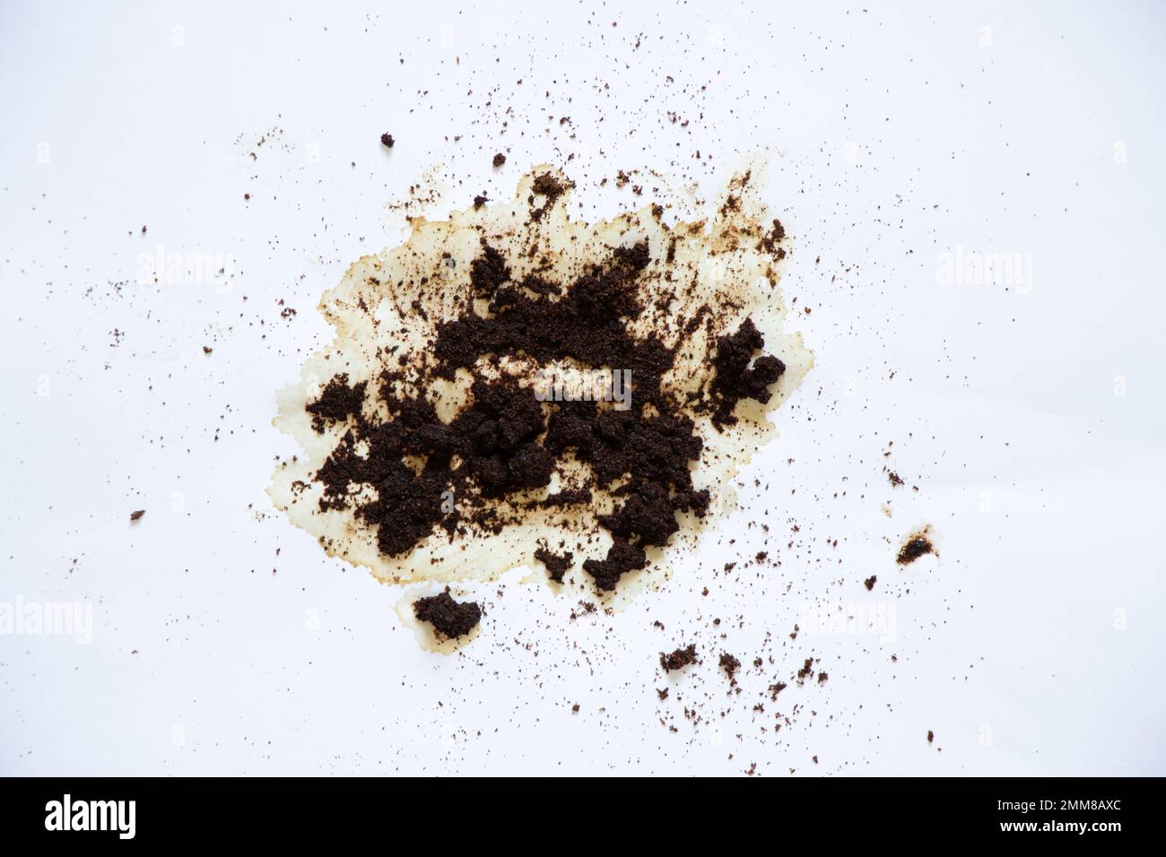 spilled coffee grounds on a white background and a teaspoon lies next to it, a coffee stain Stock Photo