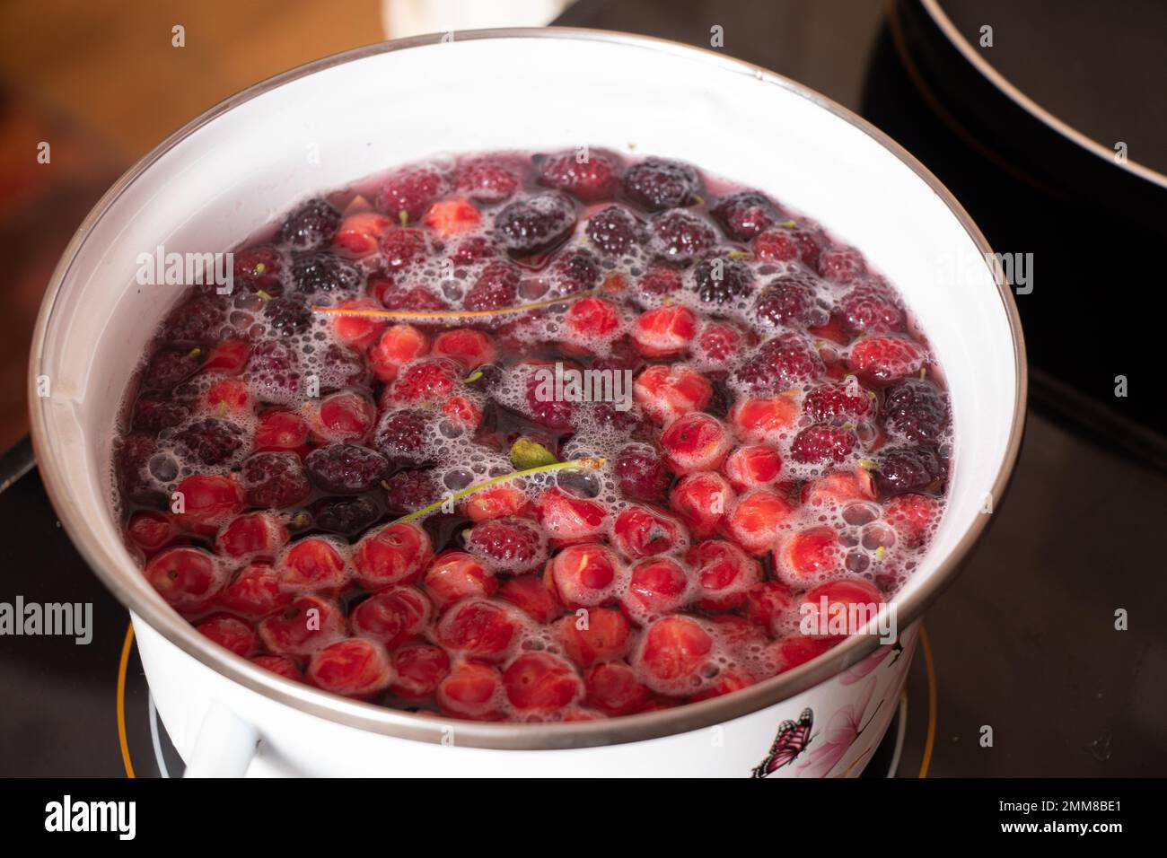 homemade fruit compote with cherry boils on the stove in the kitchen in