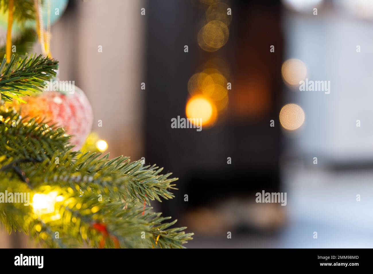 Christmas tree on the background of a burning fireplace close-up. Christmas, New Year, festive fairy-tale atmosphere, bokeh lights. Copyspace, greetin Stock Photo