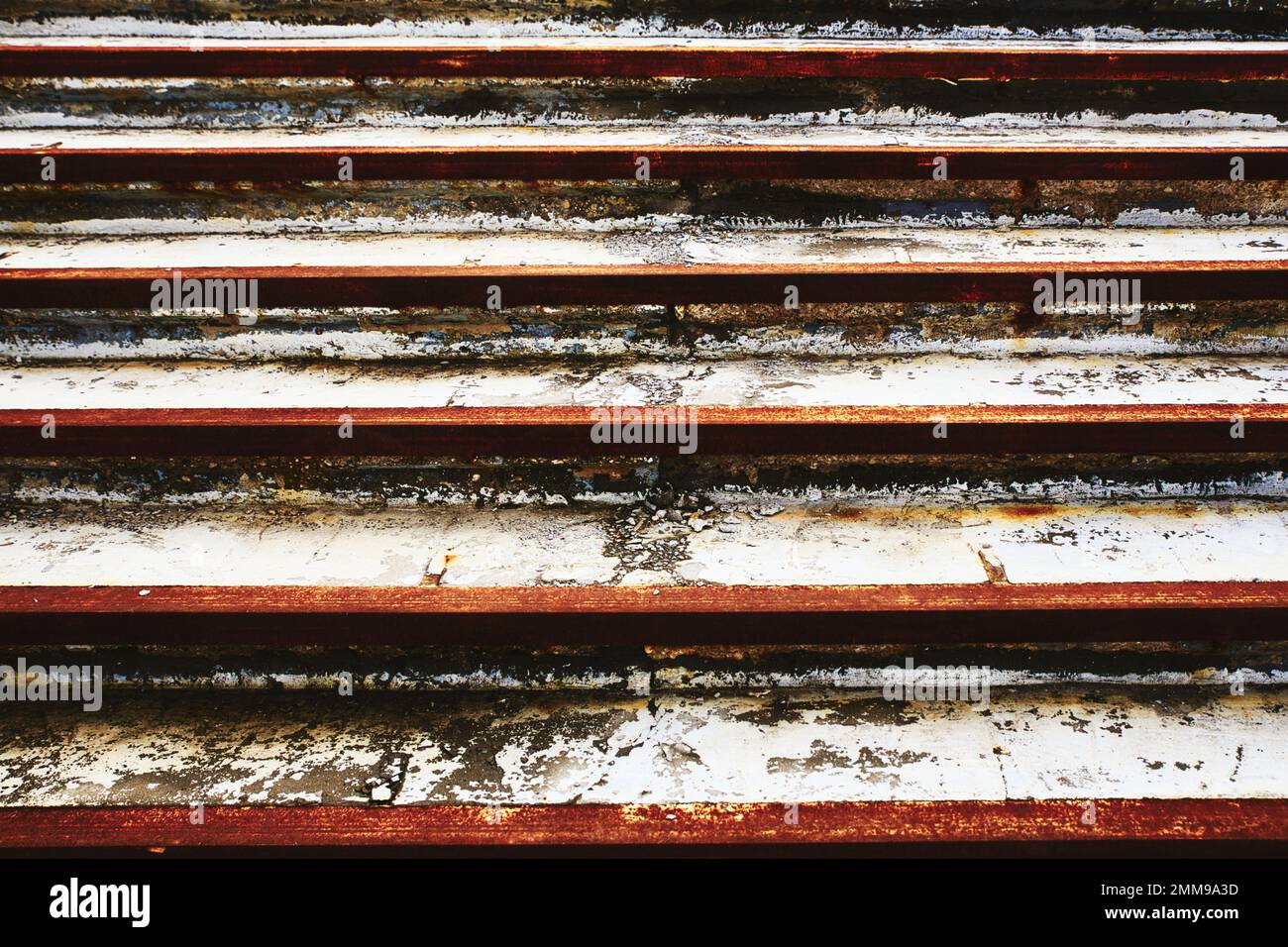 Crumbling cement steps with the edges marked by rusted orange metal strips Stock Photo