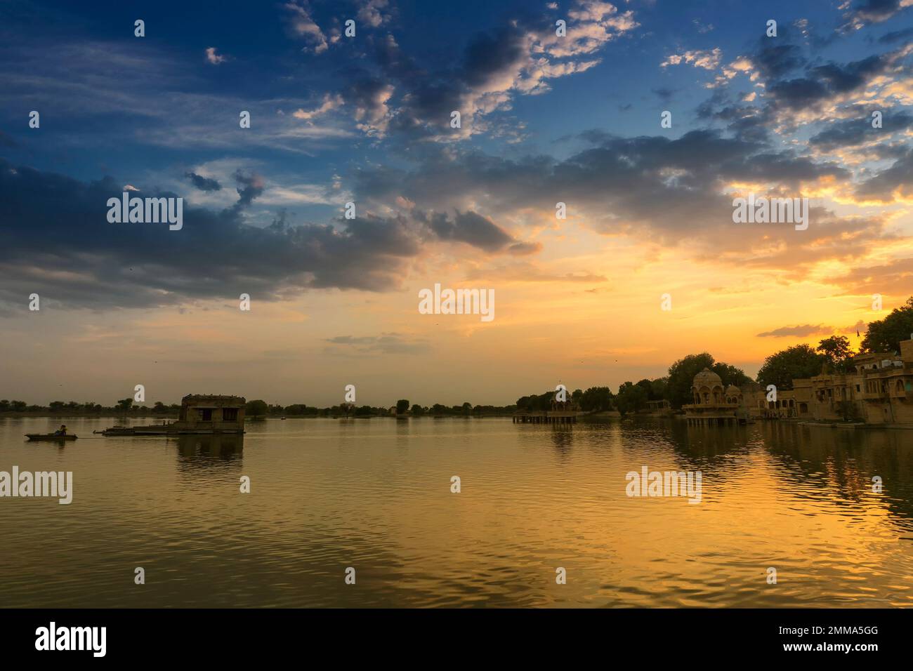 Spectacular sunset at Gadisar lake,Jaisalmer,Rajasthan, India. Setting sun and colorful clouds in the sky with view of the Gadisar lake. Tourist spot. Stock Photo