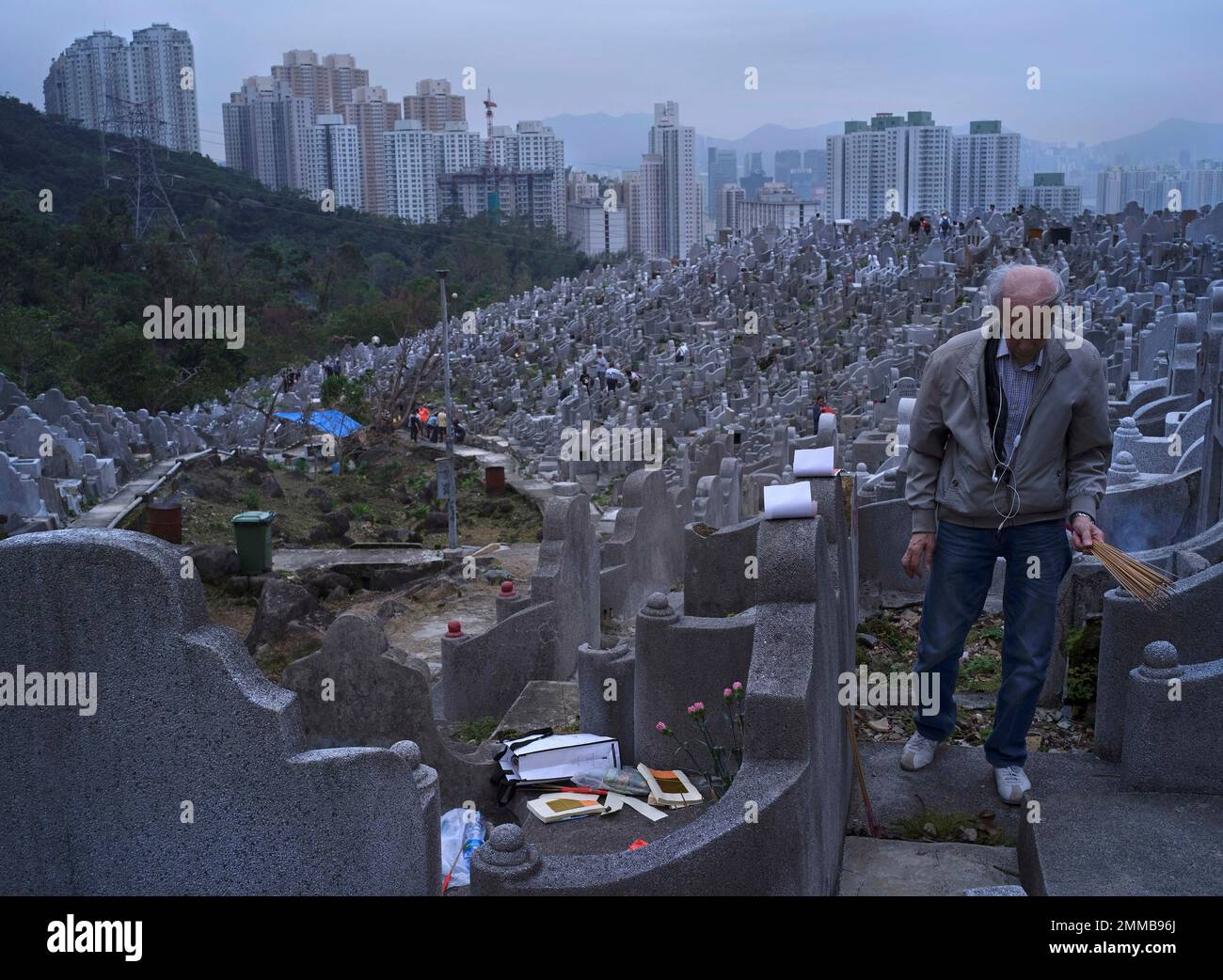 A worshipper burns incense at a cemetery as he visits the grave of his