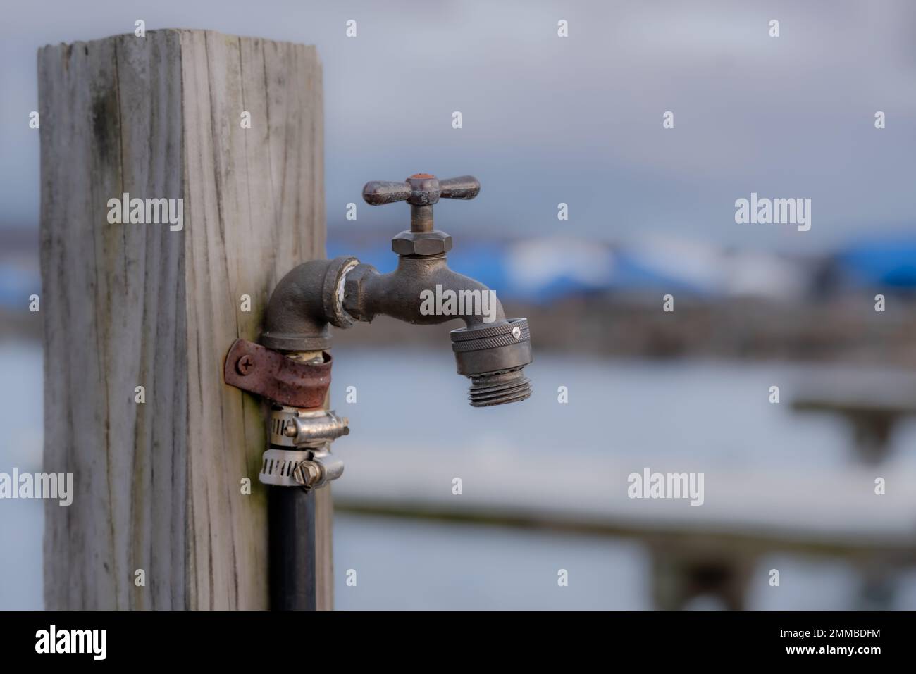 Outside water spigot, hose bib, on a wooden post. Stock Photo