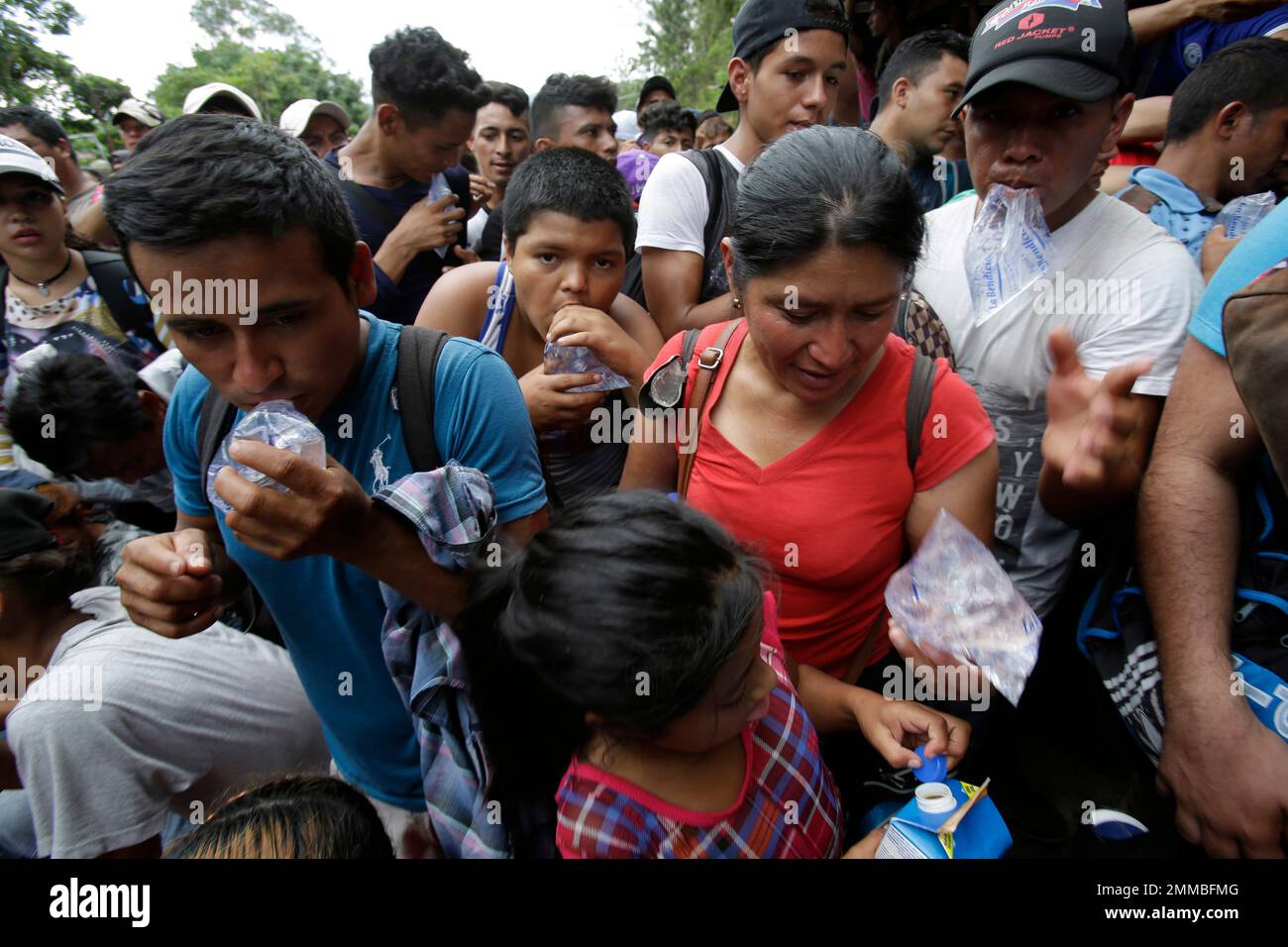 Honduran migrants drink water received from Guatemalan police agents at