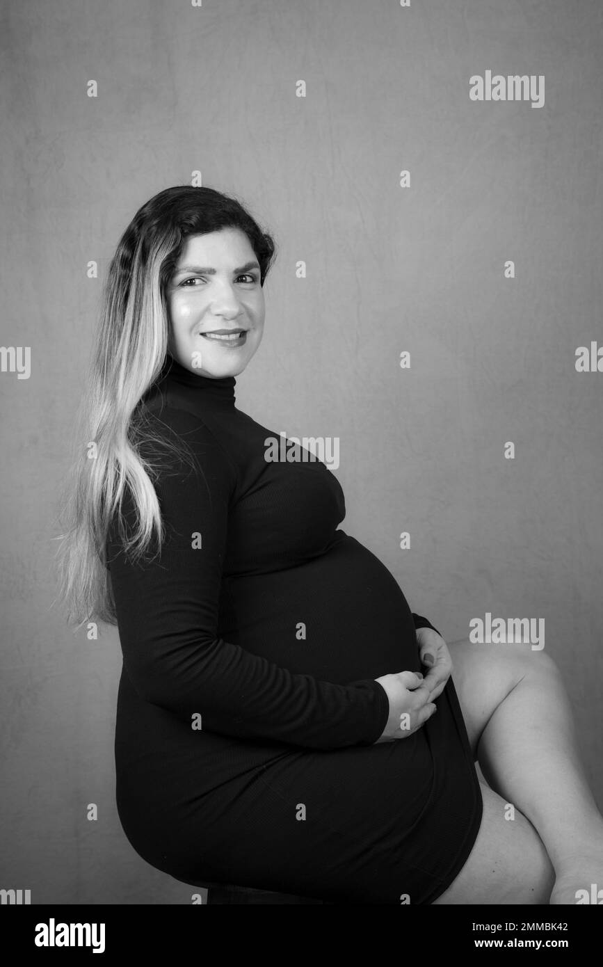 Black and white portrait of beautiful sitting pregnant woman posing. Studio portrait. Stock Photo