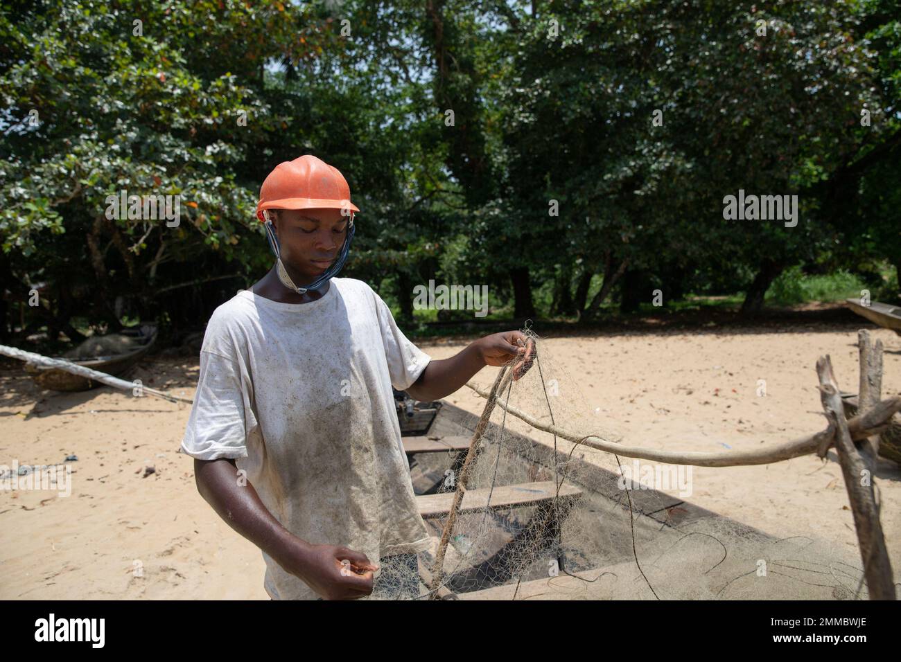 A young fisherman adjusts his net on his boat before a fishing session Stock Photo