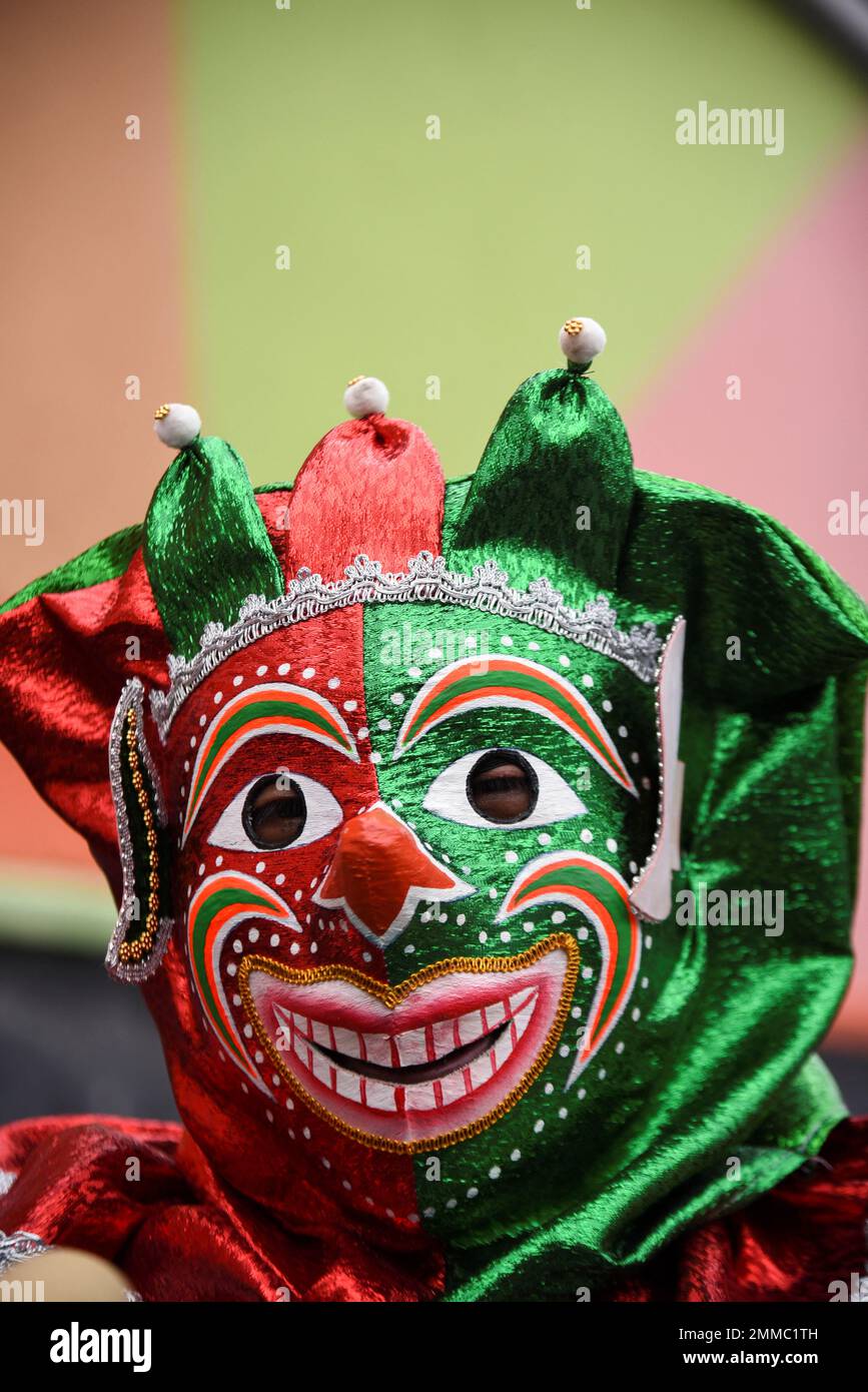 A person wears a Pepino the Cucumber mask, a carnival character, as part of  a ceremony