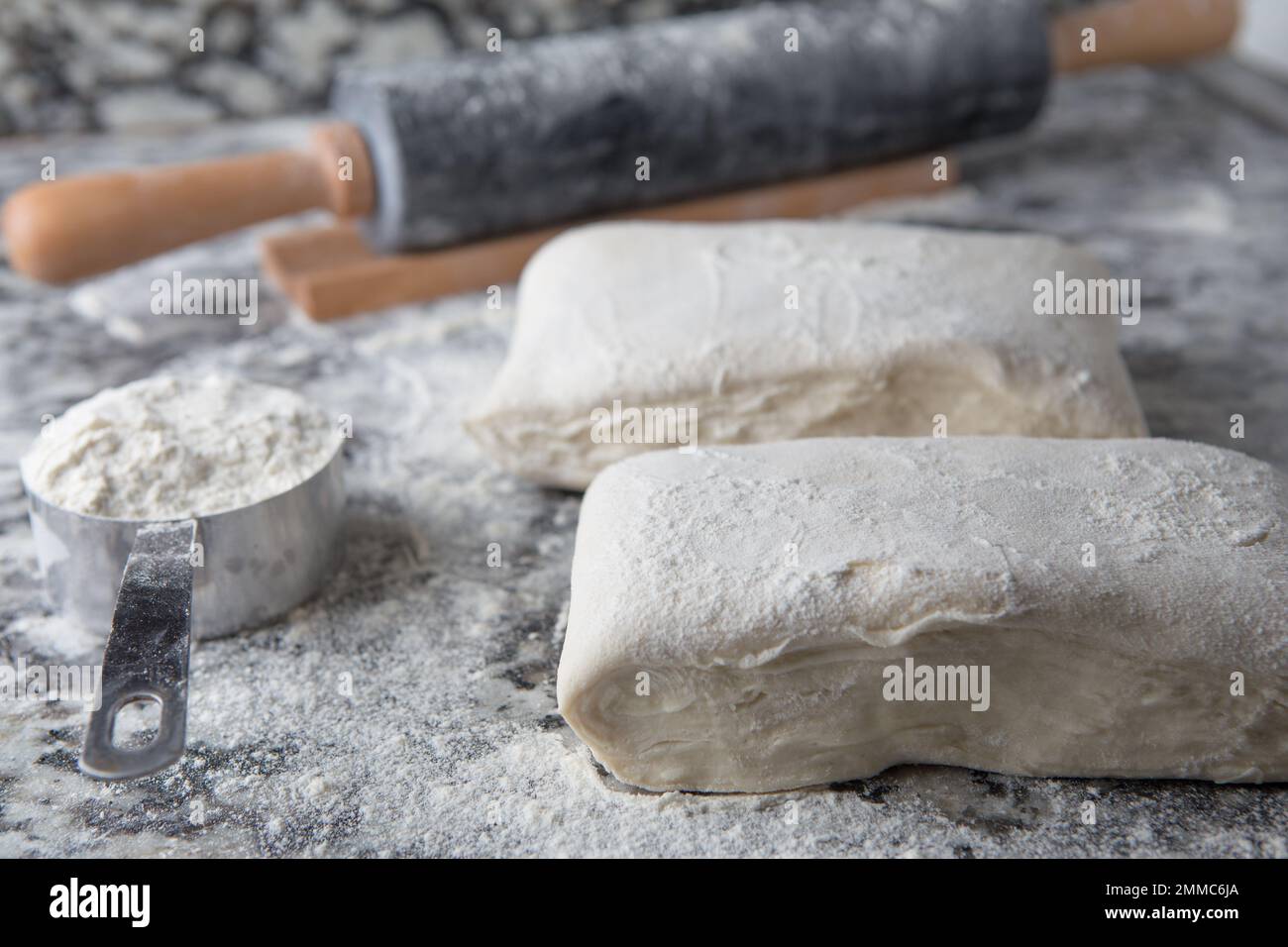 homemade Rough puff pastry with flour and a rolling pin on a marble kitchen top Stock Photo