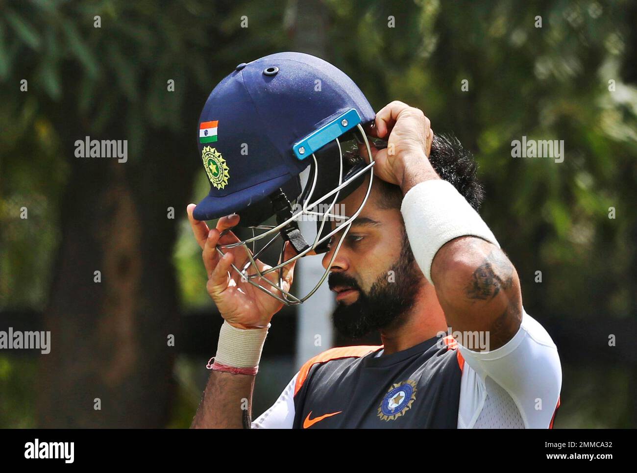 Indian cricket captain Virat Kohli prepares to wear a helmet during a  practice session ahead of their second test match against West Indies in  Hyderabad, India, Thursday, Oct. 11, 2018. (AP Photo/Mahesh