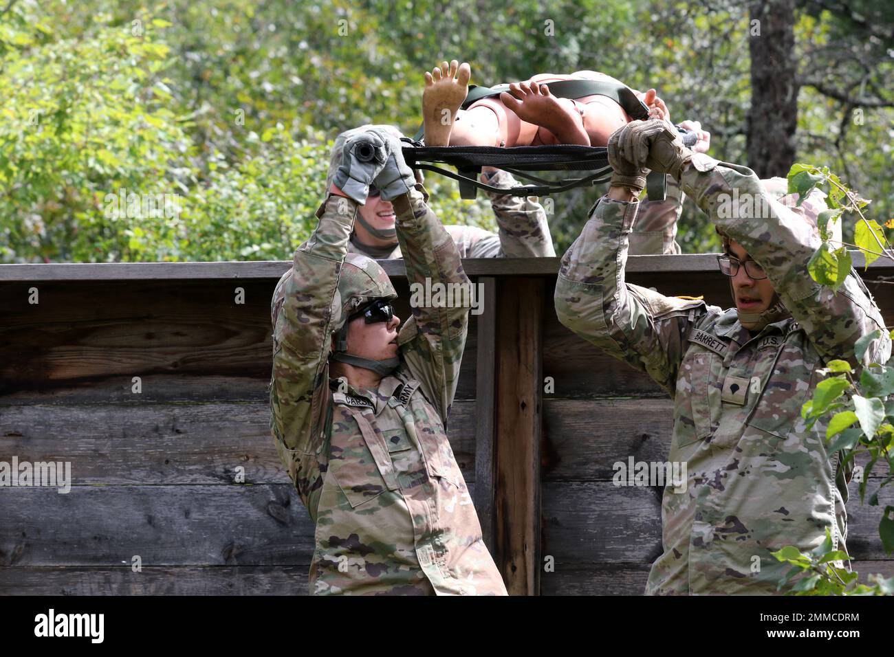 U.S. Army Reserve Spcs. Ashley Carson, left, and William Barrett, both assigned to the 452nd Combat Support Hospital, 807th Medical Command (Deployment Support) based in Milwaukee, hold a collapsible litter holding a 'casualty' above a wall as members of their squad Spc. Nicholas Radtke, left and Sgt. Matthew Breitrick steady it during a litter obstacle course on Fort McCoy, Wis., Sept. 16, 2022. Stock Photo