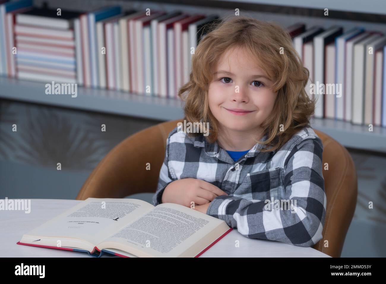 Child reading a red book in the library. Little student on school
