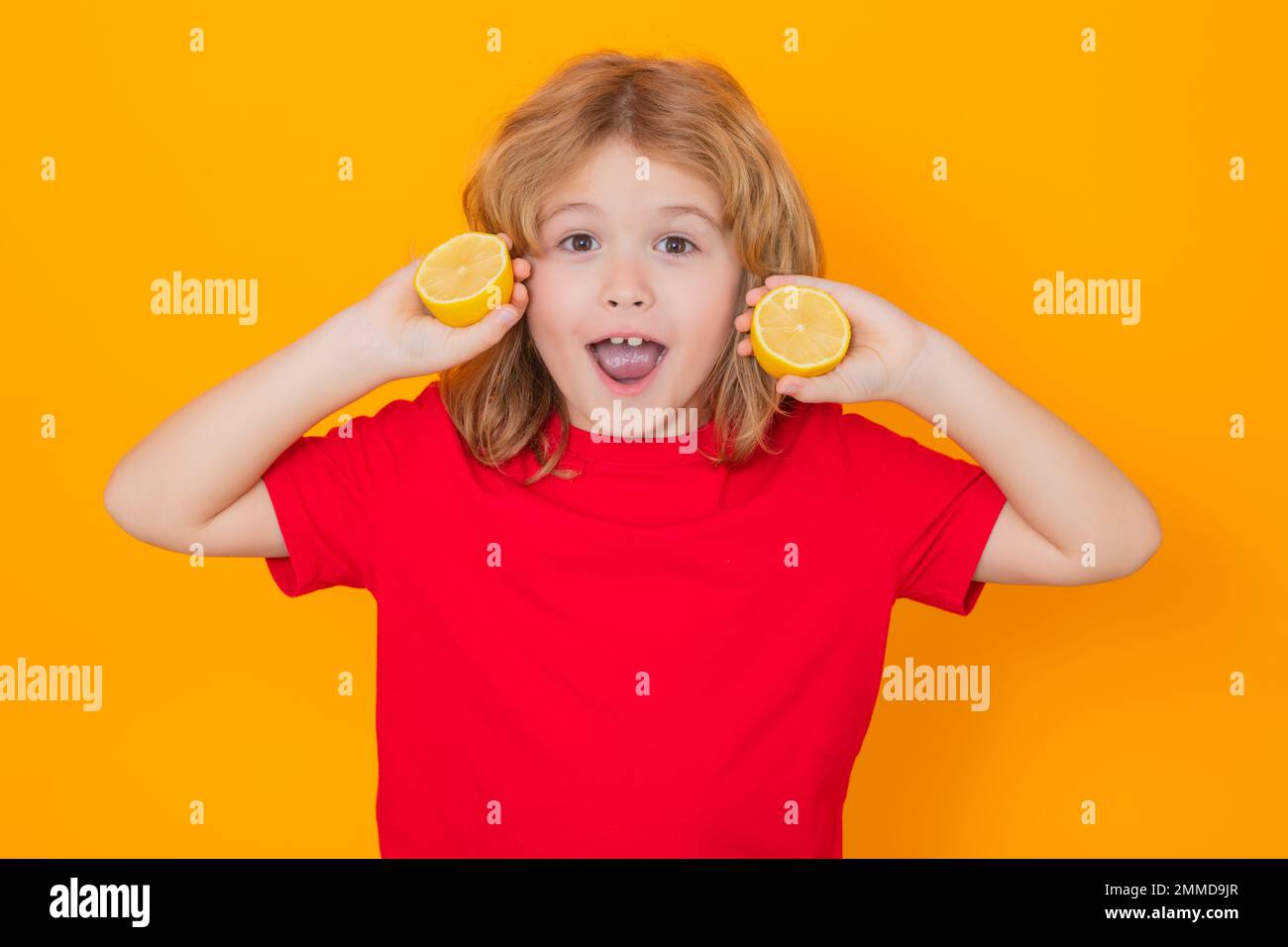 Child hold lemon in studio. Studio portrait of cute kid boy with lemon isolated on yellow. Stock Photo