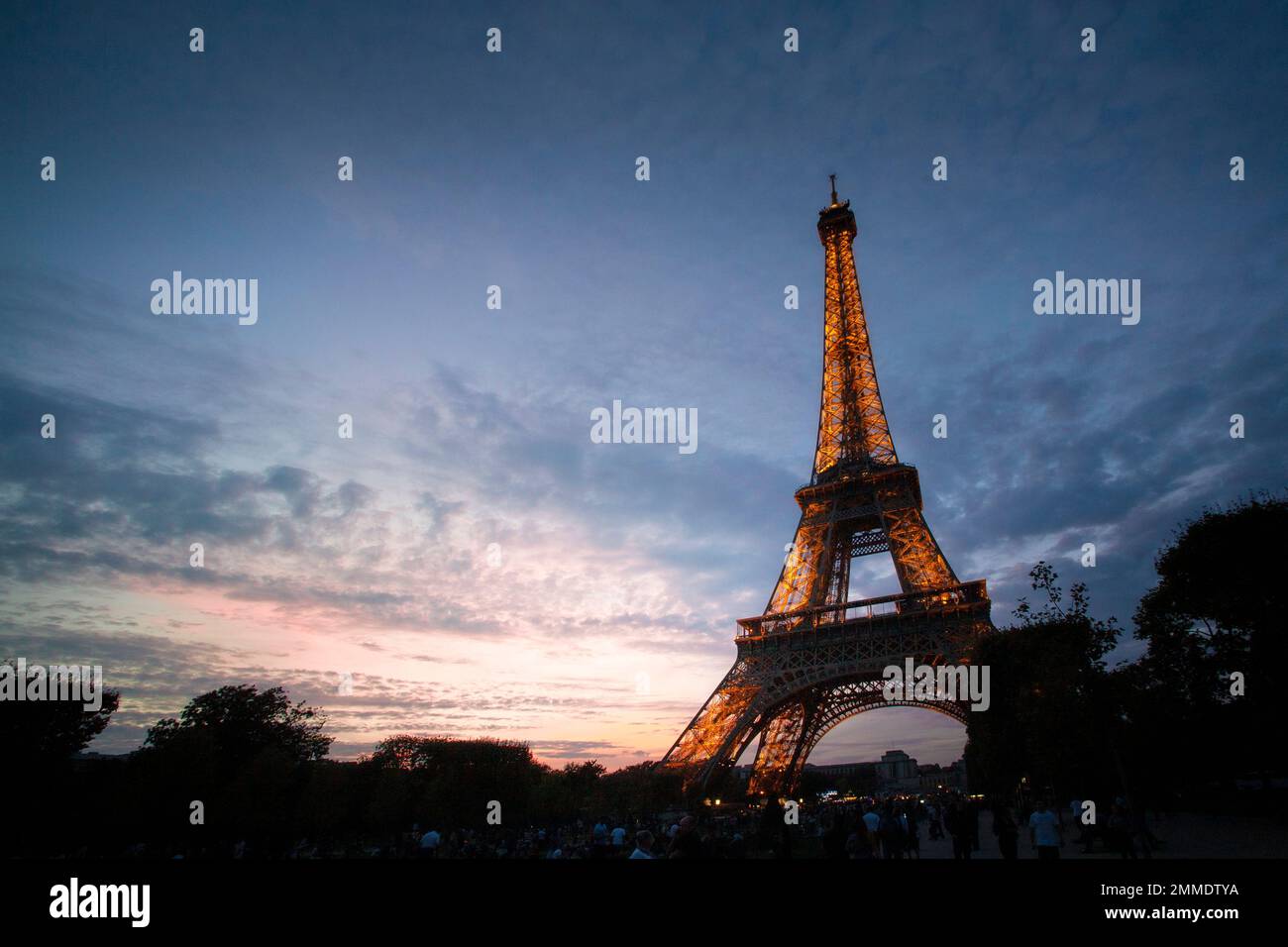 The lights come up in the Eiffel Tower as the sun fades below the