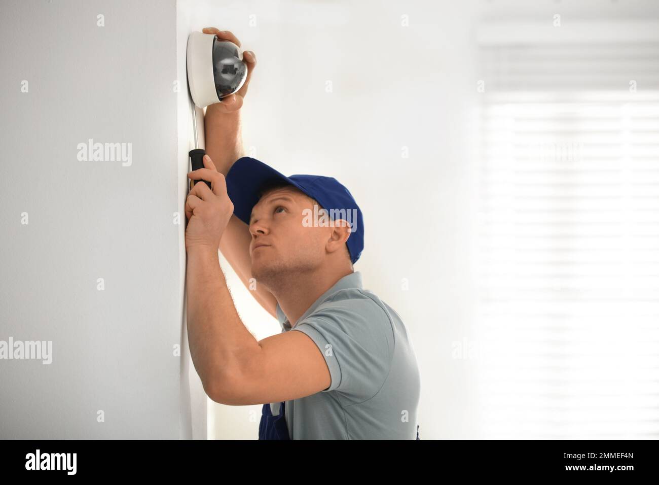 Technician installing CCTV camera on wall indoors Stock Photo