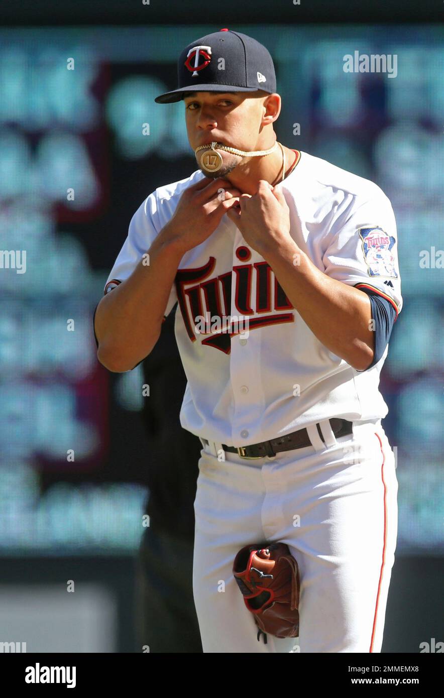 Minnesota Twins pitcher Jose Berrios holds his necklace in his mouth as he  adjusts his jersey during the fourth inning in the first game of a baseball  doubleheader against the Chicago White