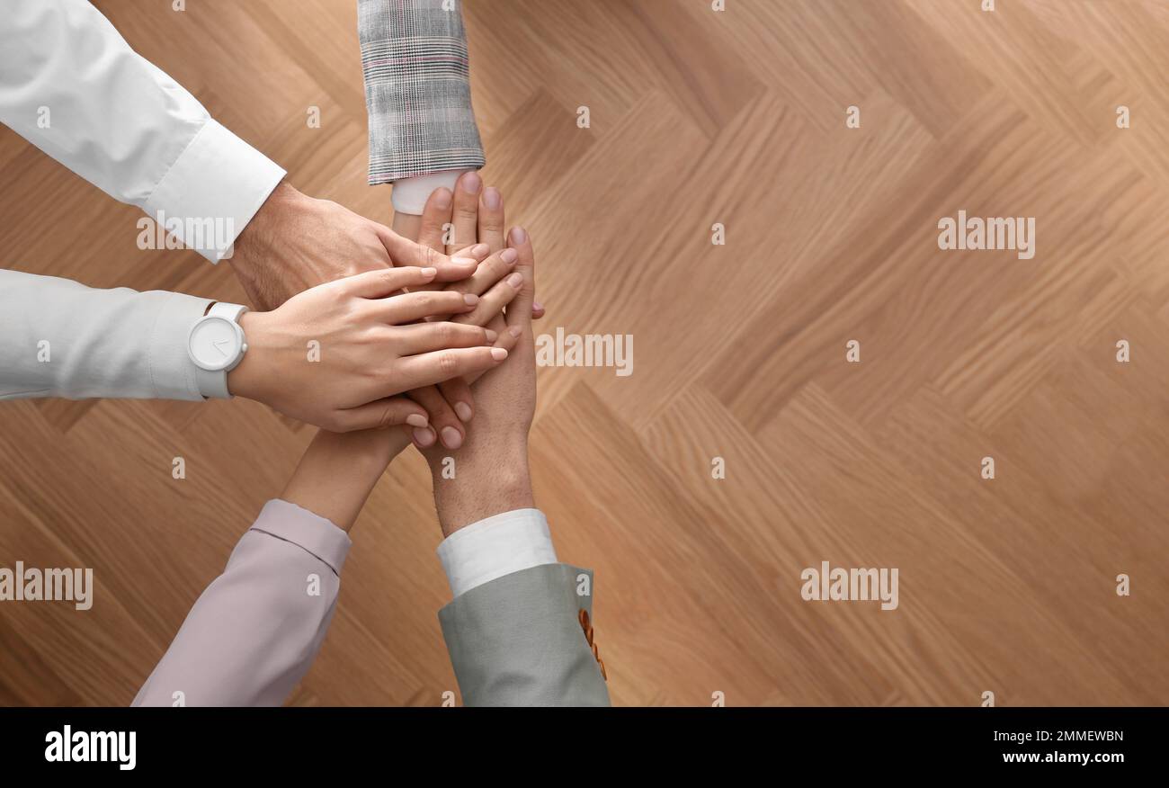 People holding hands together over wooden background, top view with ...