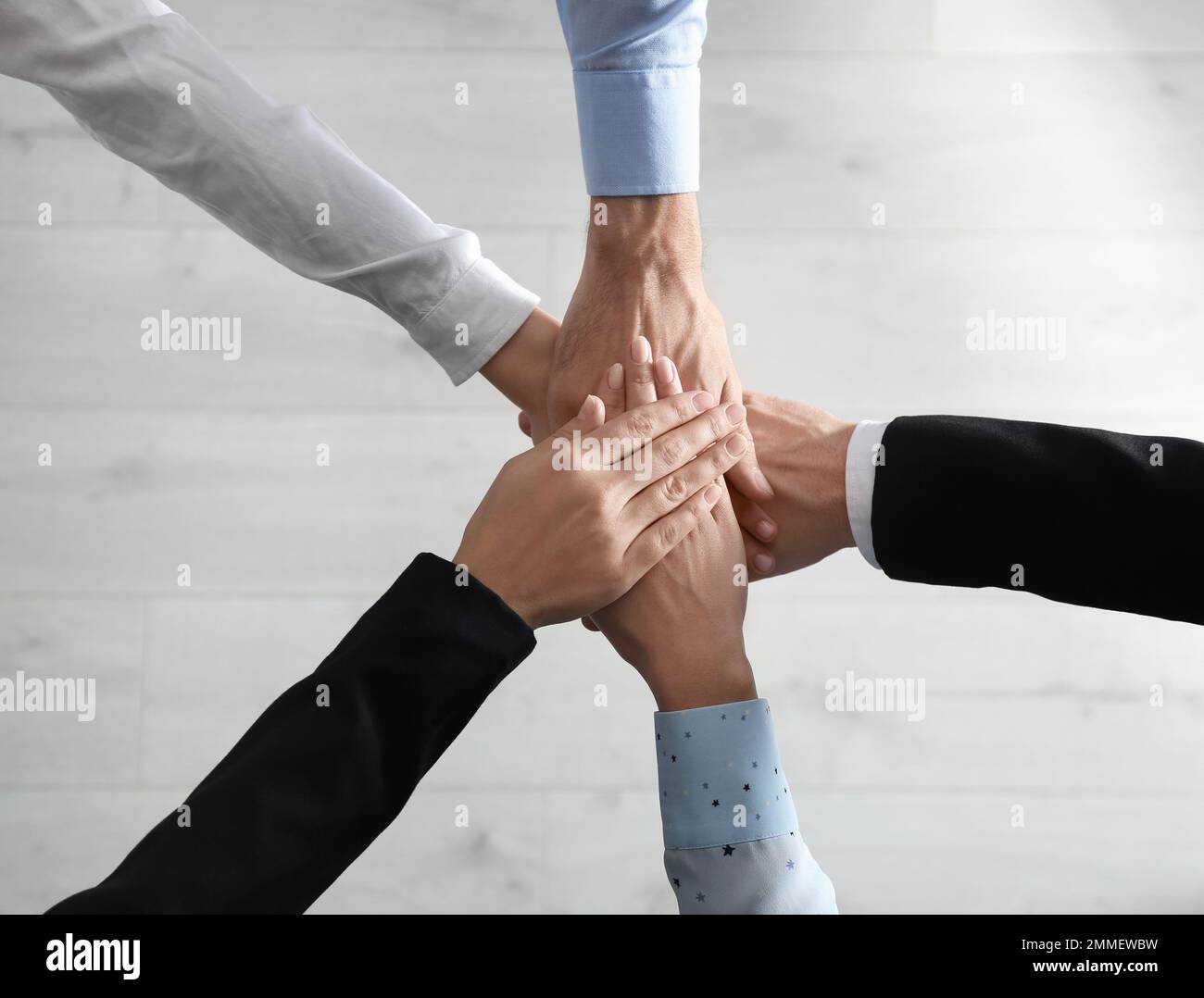 People holding hands together over light wooden background, top view ...
