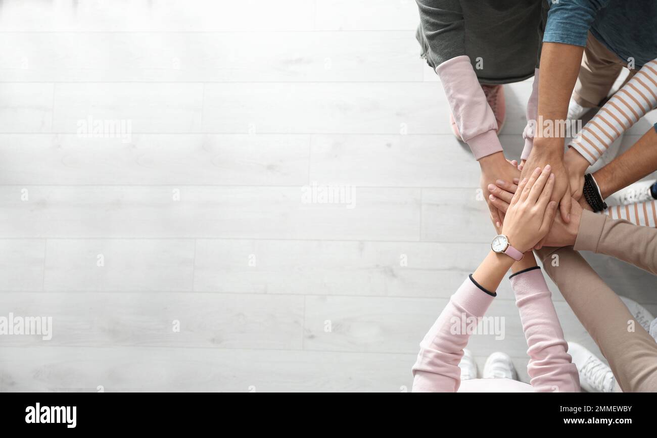 People holding hands together over light wooden background, top view ...