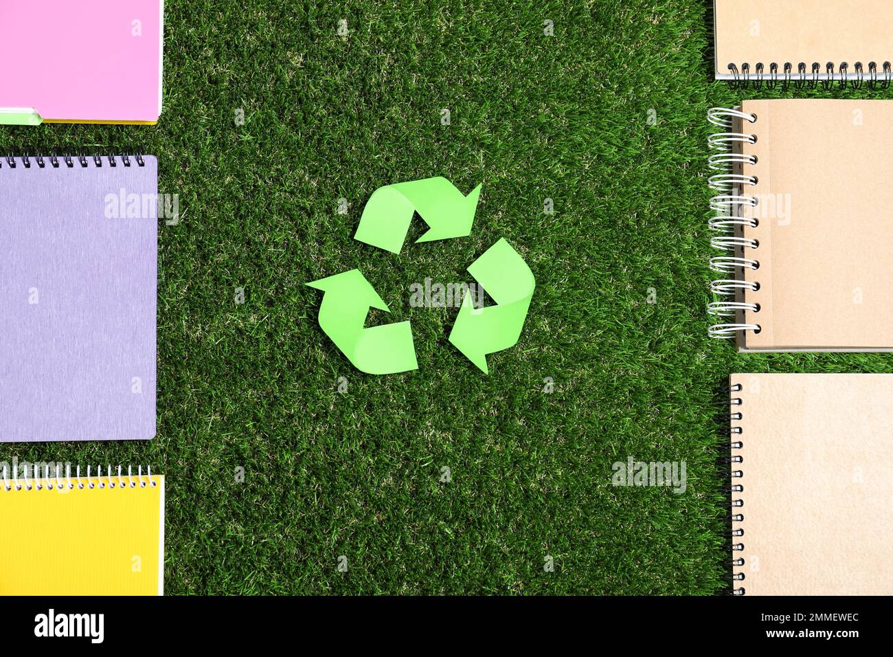 Recycling symbol, plastic and paper notebooks on green grass, flat lay Stock Photo Alamy