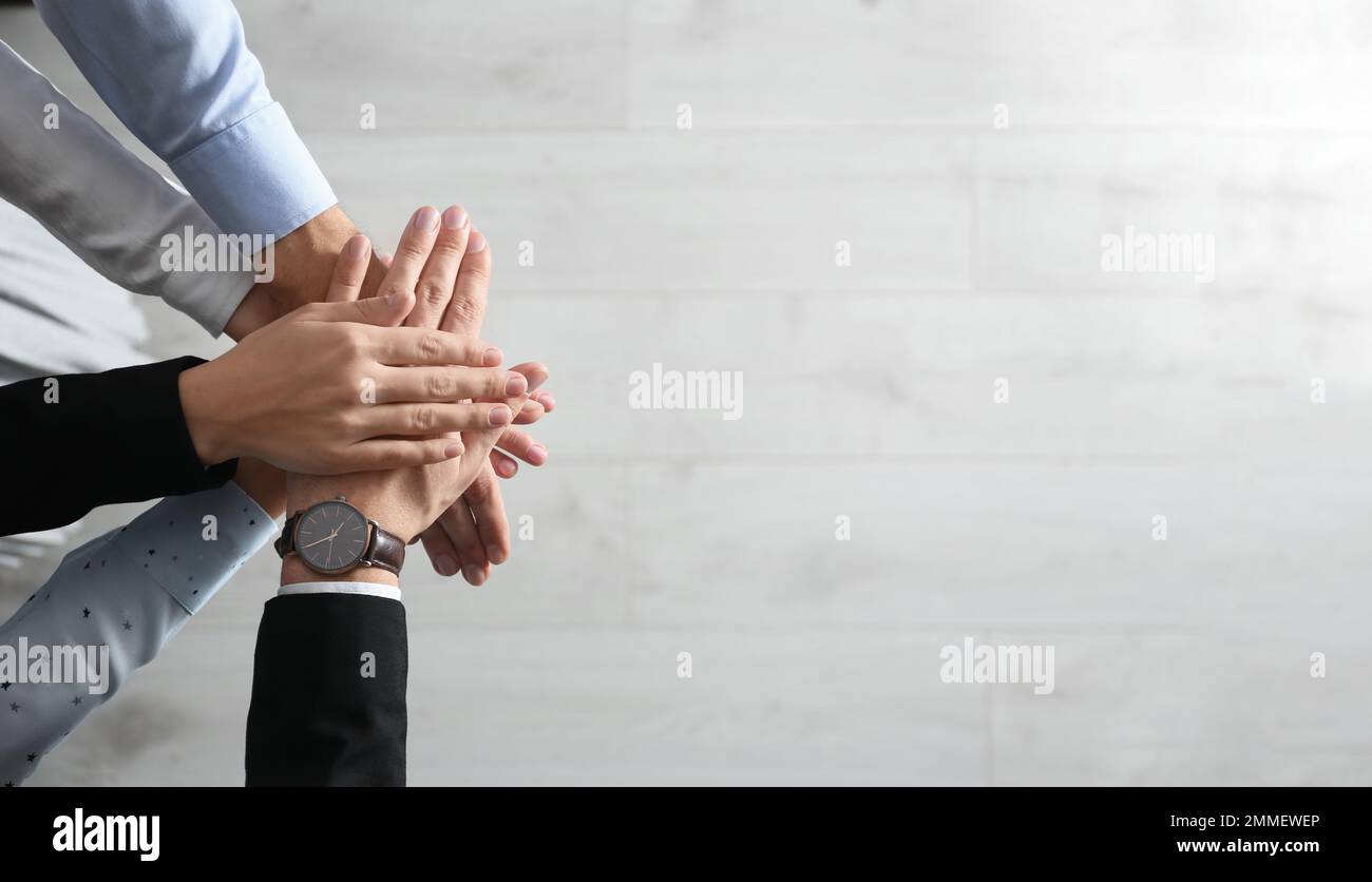 People holding hands together over light wooden background, top view ...