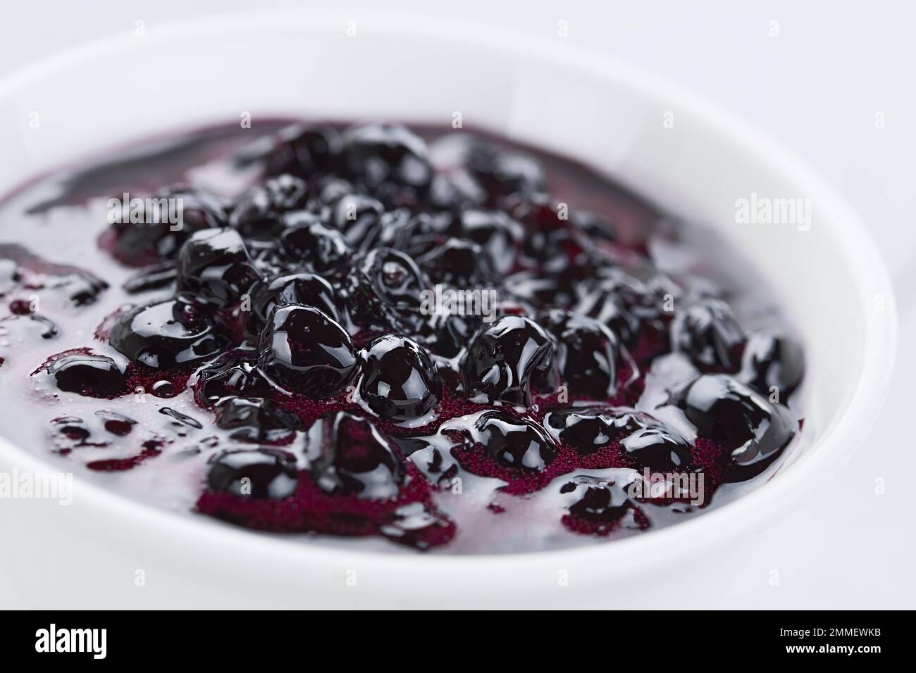 Fresh homemade jam made of Patagonian Calafate berries (lat. Berberis heterophylla), served in white bowl (Selective Focus) Stock Photo