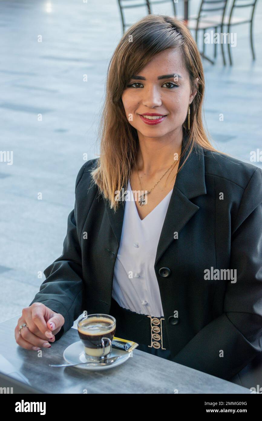 Young businesswoman takes a coffee break; she smiles at the camera. Portrait image Stock Photo
