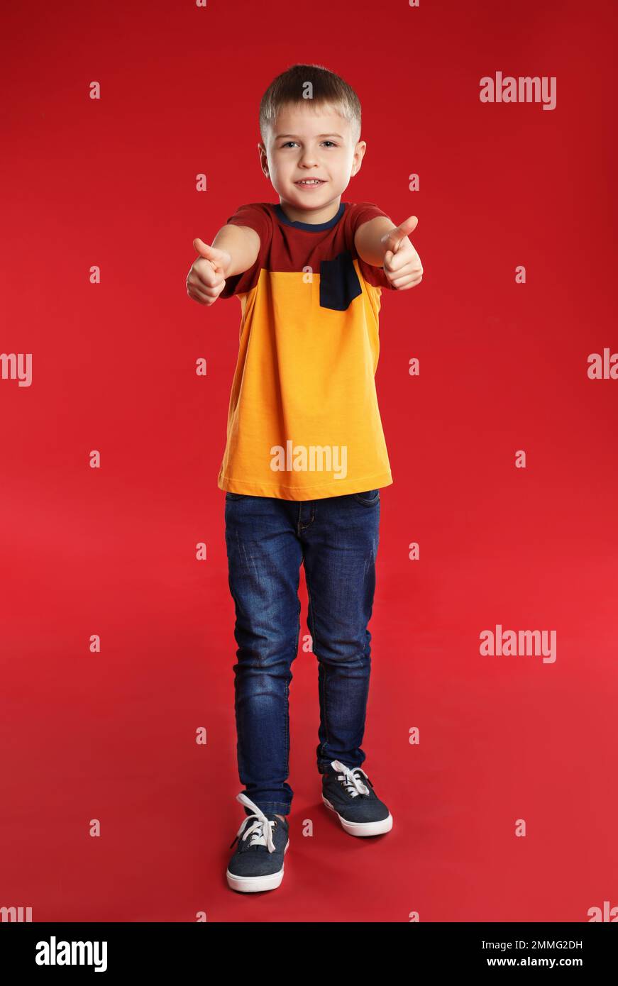 Little boy showing thumbs up on red background Stock Photo - Alamy