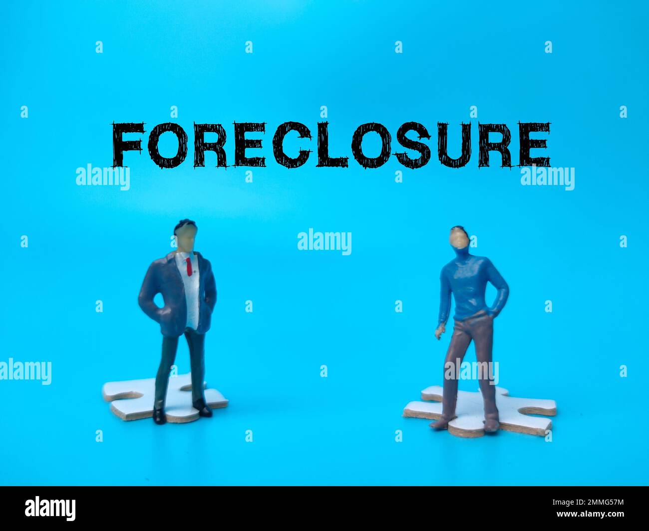 The two miniature people with the word FORECLOSURE on blue background. Stock Photo