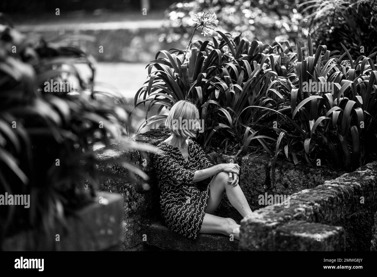 Woman on a stone bench in the ancient Park. Black and white photo. Stock Photo