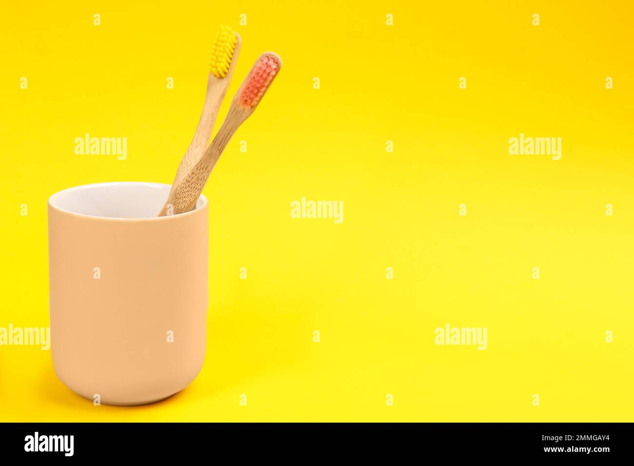 Toothbrushes made of bamboo in holder on yellow background. Space for ...