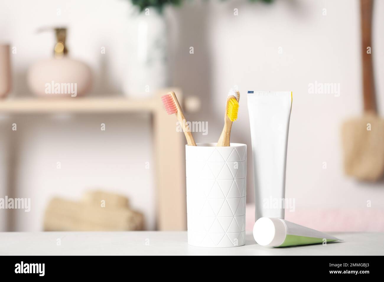 Bamboo toothbrushes and paste on light table indoors. Space for text Stock Photo