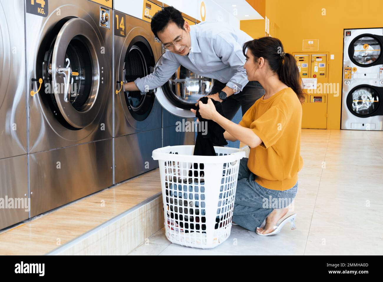 Asian people using qualified coin operated laundry machine in the public room to wash their cloths. Concept of a self service commercial laundry and Stock Photo