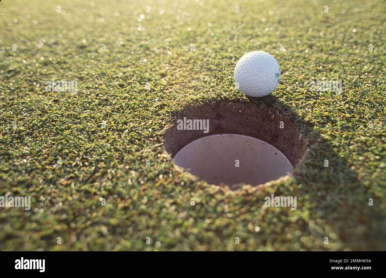 Golf ball sitting on the edge of the cup, missed shot Stock Photo