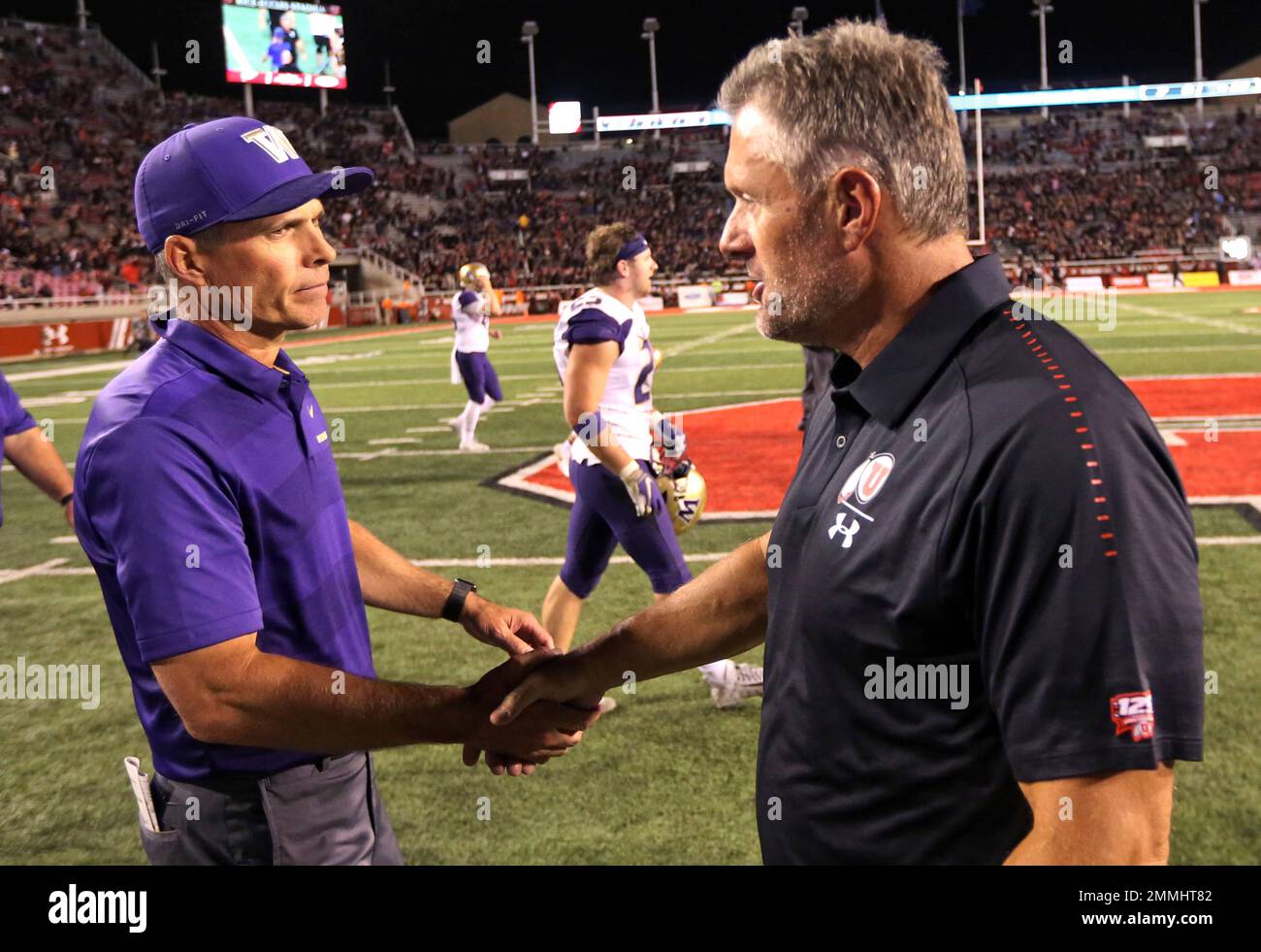 Washington head coach Chris Petersen, left, shakes hands with Utah head