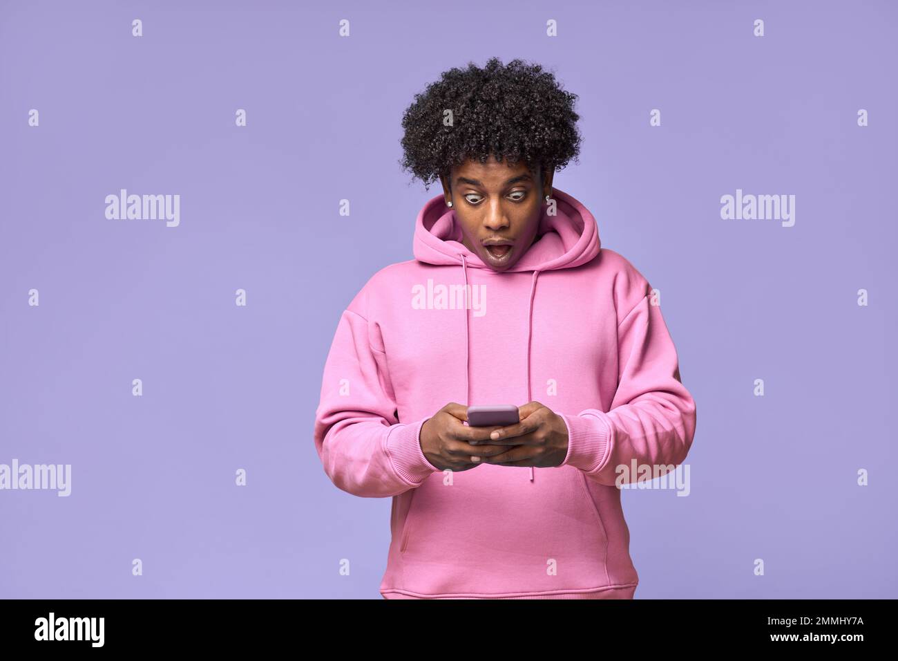 Surprised African teen guy looking at phone receiving message with promotion. Stock Photo