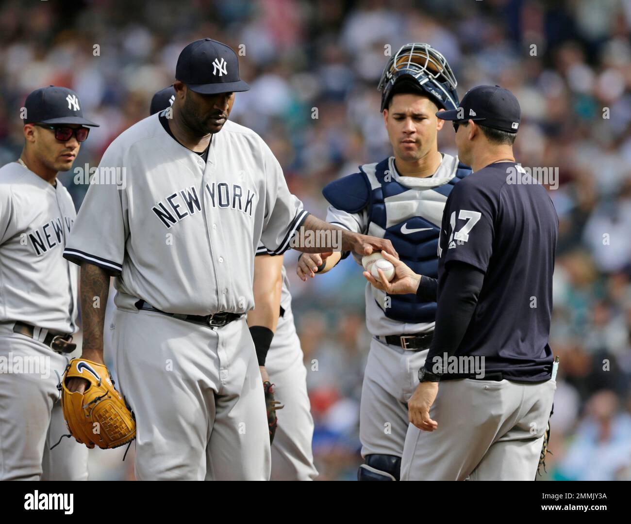 New York Yankees starting pitcher CC Sabathia hands the ball to Aaron Boone  who is already holding a baseball as he is replaced against the Seattle  Mariners during the sixth inning of