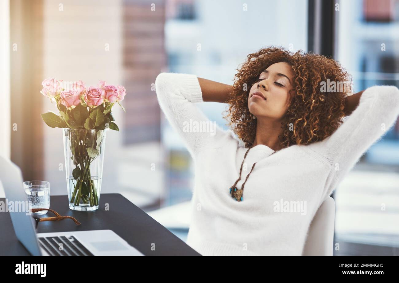 Its easy when you love what you do. a young entrepreneur leaning back in her chair with her hands behind her head. Stock Photo