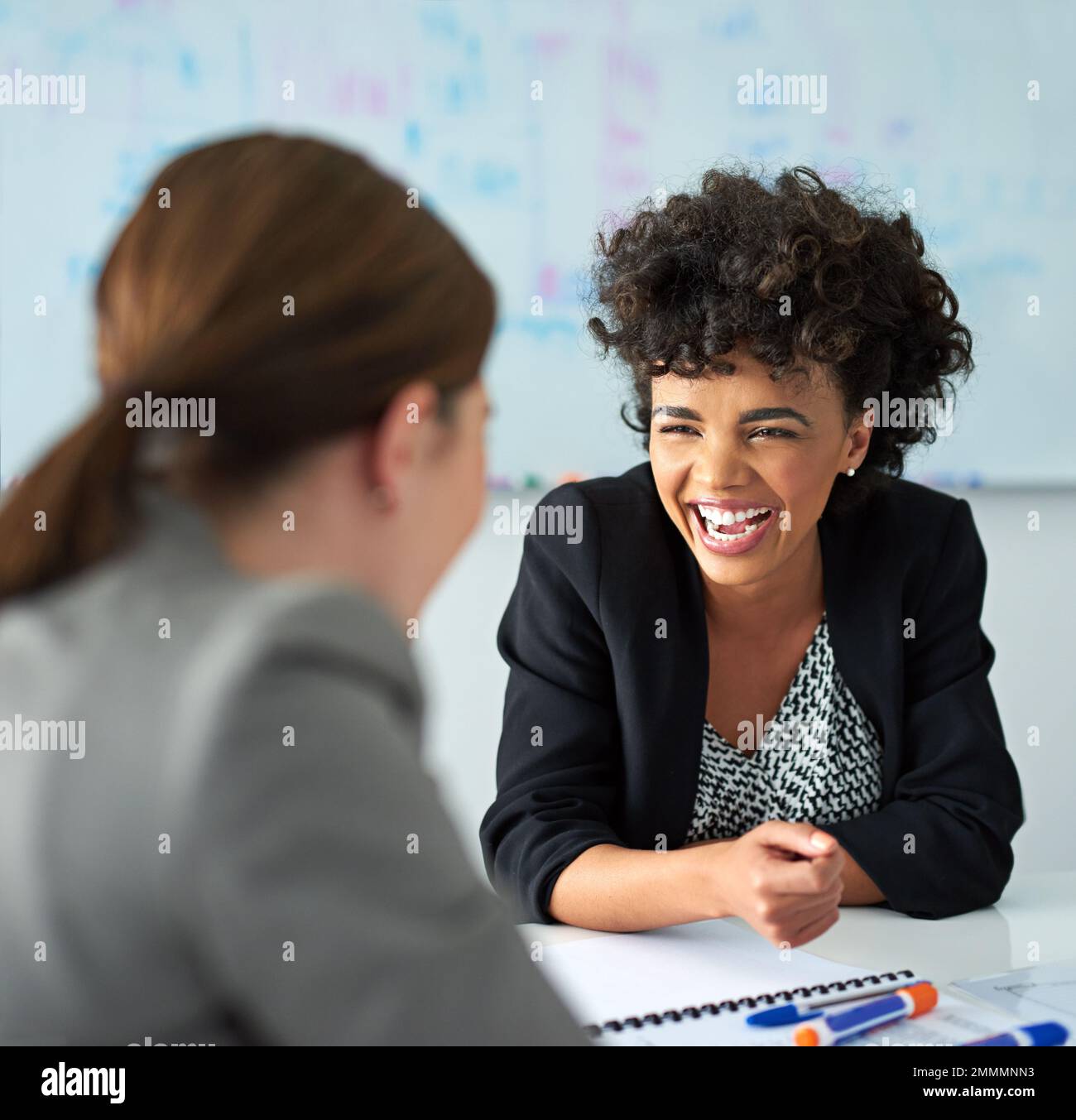 Cracking up over some office humor. two businesswomen enjoying a meeting together at work. Stock Photo