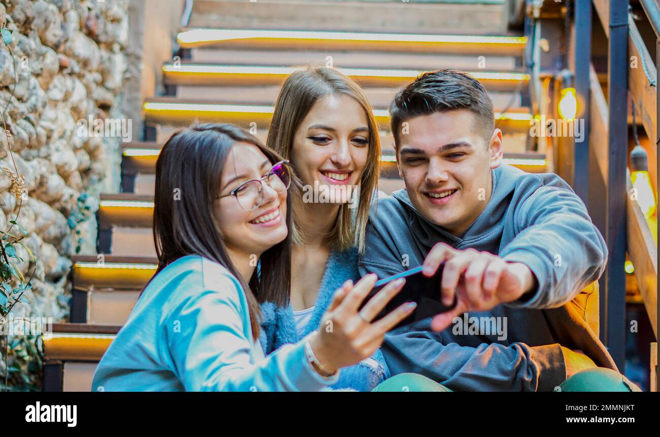 Young people using smartphone together - Students having fun with  cellphone Stock Photo
