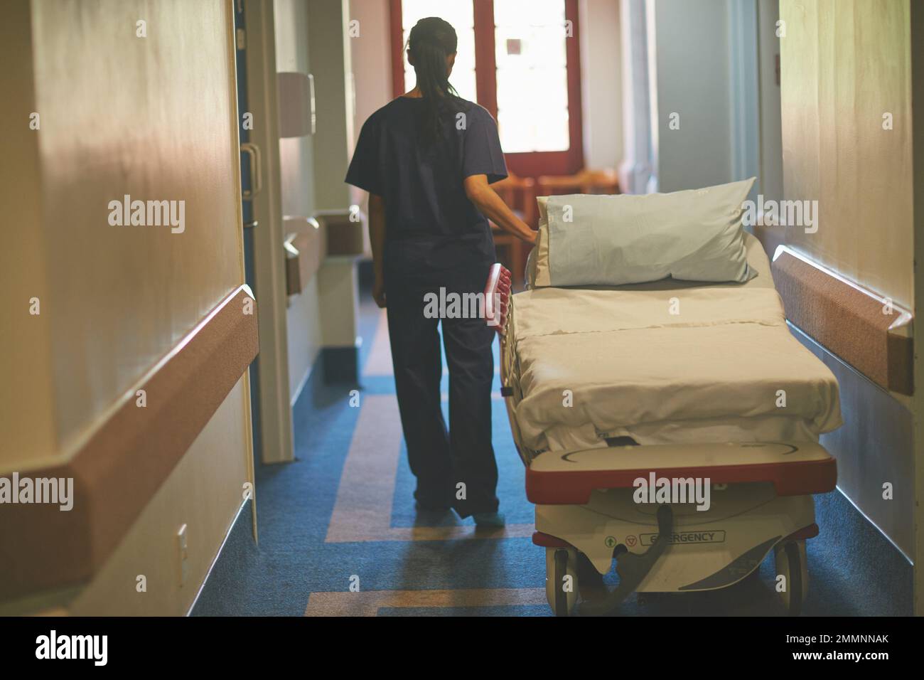 Taking the hospital bed to the correct ward. Rearview shot of a female nurse pushing a hospital